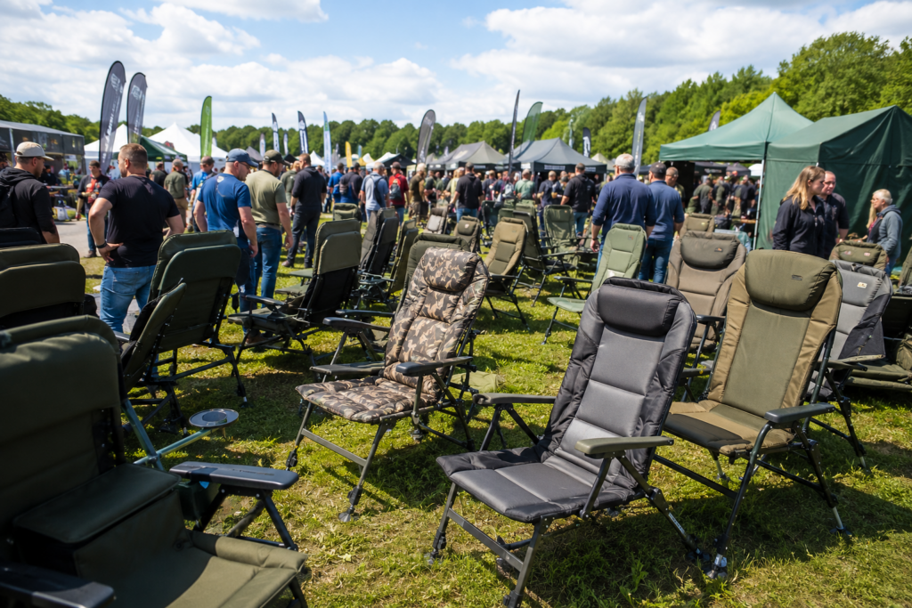 Verschiedene Angelstühle auf einer großen Outdoor Messe mit Besuchern im Hintergrund