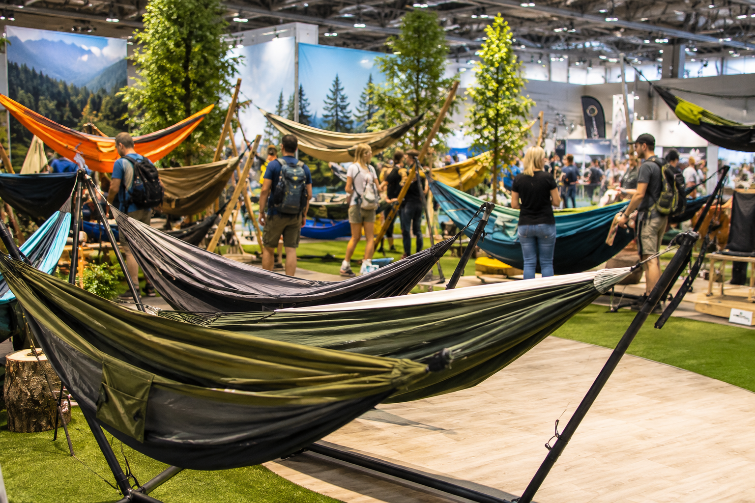 Verschiedene Camping Hängematten auf einer Outdoor Camping Messe mit Besuchern im Hintergrund