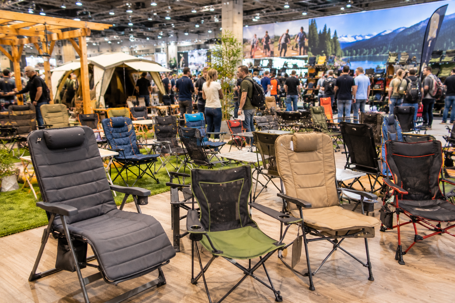Verschiedene Campingstühle auf einer Outdoor Messe mit Besuchern im Hintergrund