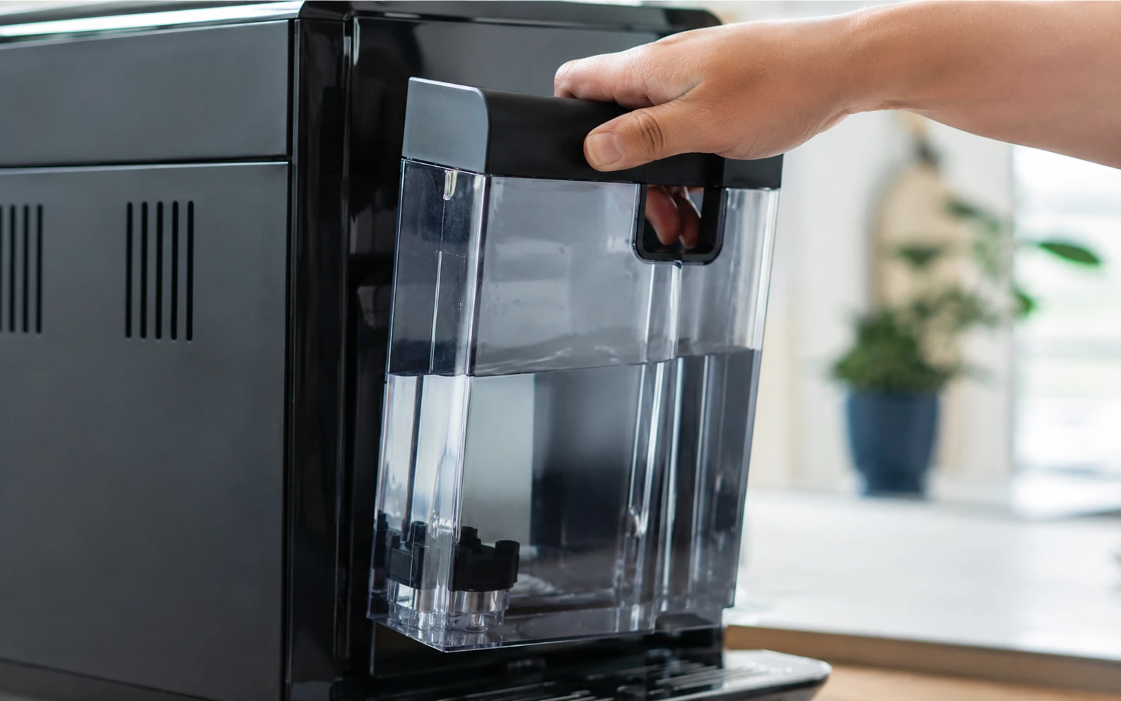 Wassertank eines Kaffeevollautomaten wird für die Reinigung herausgezogen