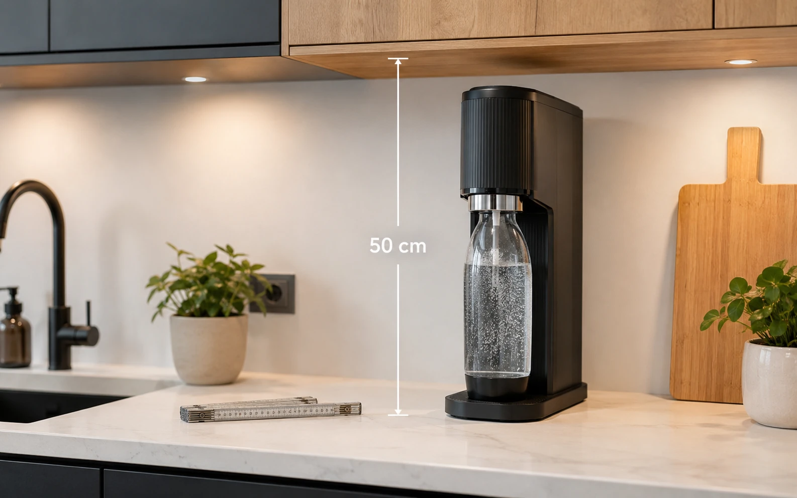 Ein schwarzer Wassersprudler steht unter einem Küchenschrank mit einer eingeblendeten Höhenmarkierung von 50 cm